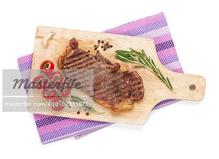Sirloin steak with rosemary and cherry tomatoes on a cutting board. Isolated on white background. View from above