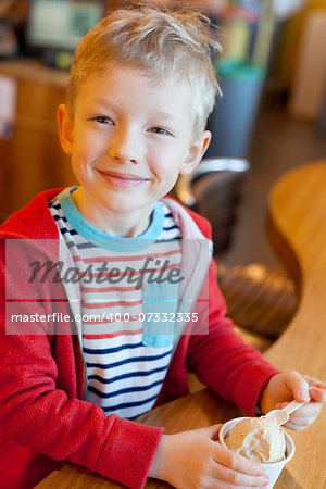 happy smiling little boy eating ice cream in cafe