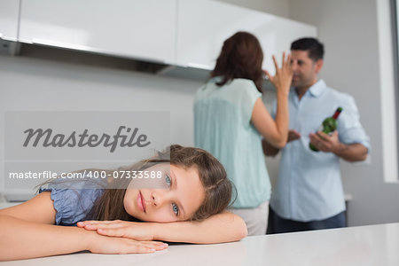 Closeup portrait of a sad girl while parents quarreling in the kitchen