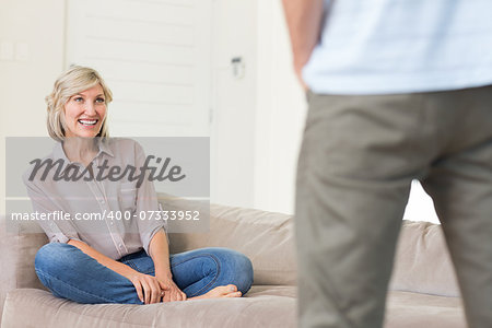 Smiling woman looking at standing man in the living room at home