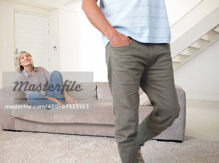 Smiling woman looking at walking man in the living room at home
