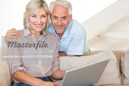 Portrait of a happy mature couple using laptop on sofa at home