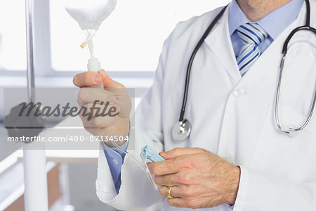 Mid section of male doctor examining IV drip in hospital