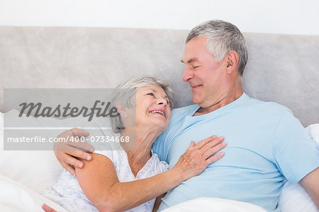 Loving senior man looking at wife in bed at home