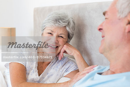 Portrait of happy senior woman with man in bed at home