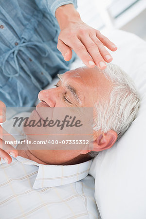 Closeup of senior man receiving Reiki treatment by therapist at health spa