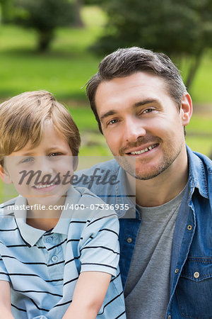 Close-up portrait of a father and young boy sitting at the park