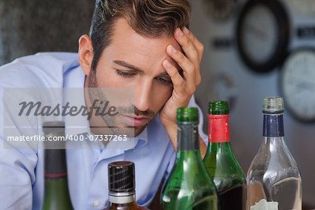 Drunk businessman looking at spirit bottles at the local bar