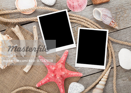 Blank photo frames with ship rope and seashells over wooden background