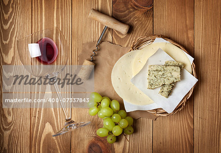 Red wine, cheese and grape on wooden table background