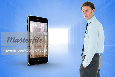 Serious businessman standing with hands in pockets against bright blue room