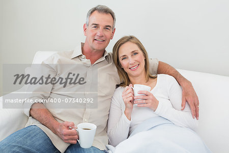 Relaxed loving couple with coffee cups in living room at home