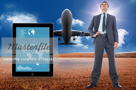 Serious businessman with hand on hip against 3d plane taking off over cornfield