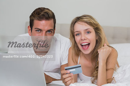 Happy young couple doing online shopping through laptop and credit card at home