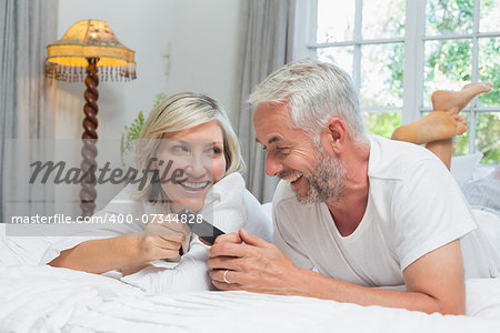 Close-up of a cheerful mature couple reading text message at home