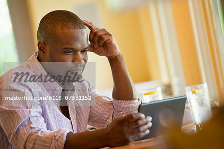 A man in a cafe, using a digital tablet.