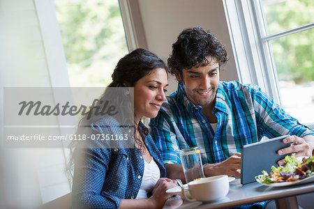 A couple seated looking at a digital tablet.