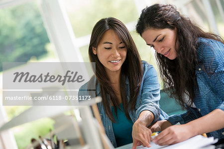 Two women working together, looking at the screen of a digital tablet.