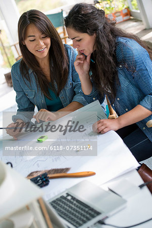 Two women working together, looking at the screen of a digital tablet.