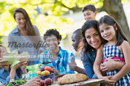 A summer party outdoors. Adults and children smiling and looking at the camera.