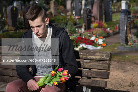 Teenager Sitting on Bench in Cemetery