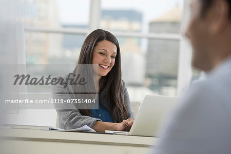 An office or apartment interior in New York City. A man and woman seated across a table talking.