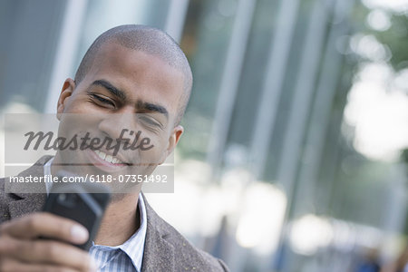 Business people in the city. Keeping in touch on the move. A man looking down at his smart phone.