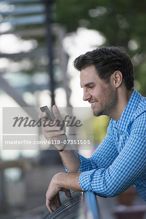 Business people in the city. Keeping in touch on the move. A man in a blue shirt, using a smart phone.