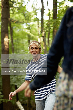 Two people walking along a fallen tree trunk in the woods.