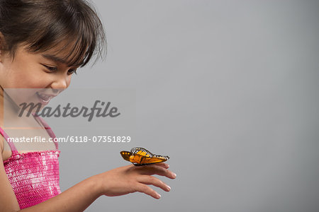 A child with a butterfly on her hand, keeping very still.