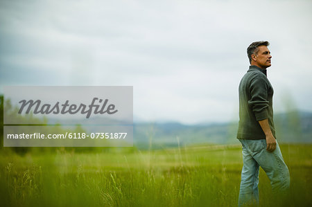 A man standing alone looking into the distance, deep in thought.