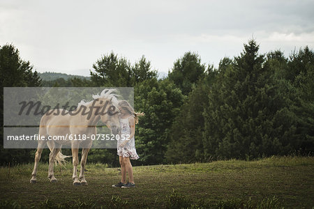 A young girl with a palomino pony in a field.