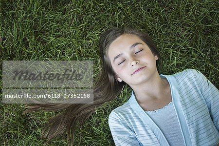 A girl with long hair fanned out, asleep on the grass.