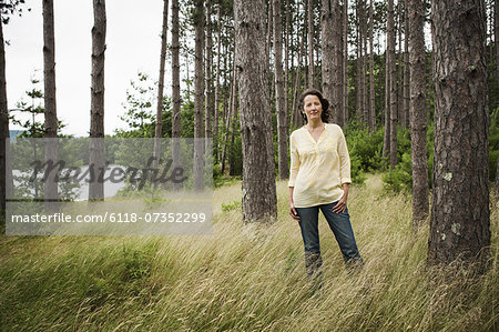 A woman in open countryside, by a mountain lake.