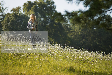 A young woman walking in a wild flower meadow.