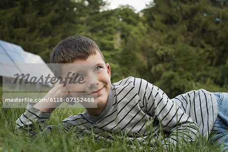 A boy lying in the grass, beside solar panels.