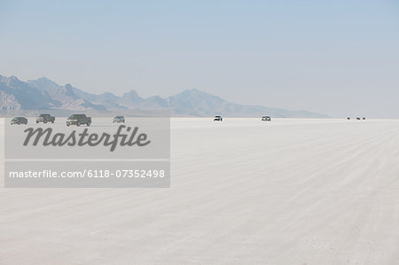 Cars driving on Bonneville Salt Flats during Speed Week. Dusk.