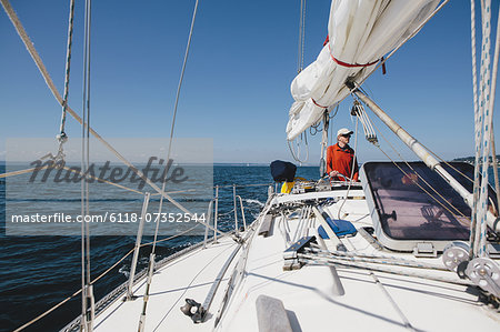 Middle aged man steering sailboat on Puget Sound, Washington, USA