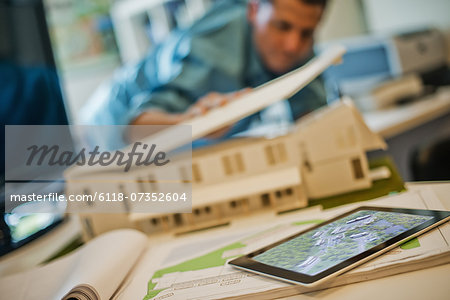 Architects working on a green construction project, using computer technology, in an office. An architect's model of a house. Computer tablet.