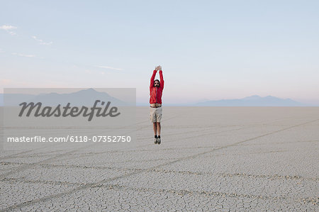 A man jumping in the air on the flat desert or playa or Black Rock Desert, Nevada.