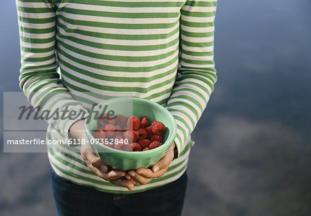 Nine year old girl holding bowl of organic raspberries