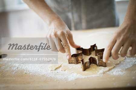 Woman making organic Christmas cookies, cutting dough with a cookie cutter.