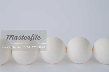 End-on view of free range, organic eggs with white shells arranged in a row, on a white background. End-on view of free range, organic eggs with white shells arranged in a row, on a white background.