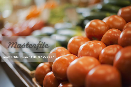 A farm stand display of fresh produce. Tomatoes and cucumbers.