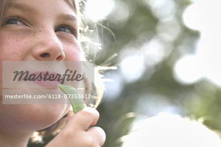 A child, a young girl eating a freshly picked organic snap pea in a garden.