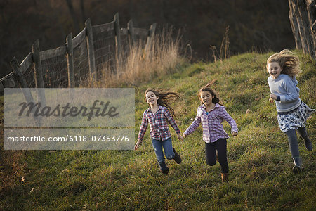 Three children running down a hill on an organic farm.