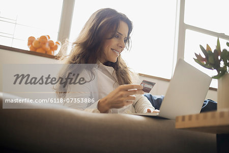 Woman on-line shopping on laptop on sofa with credit card