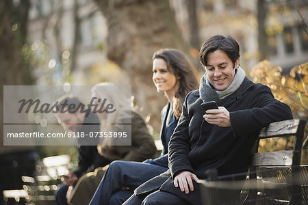 Group on bench in urban park using smartphones