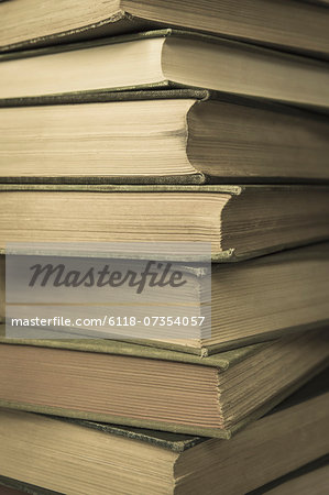 A stack of old hard cover books, with worn edges and aged yellowing paper.