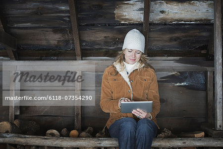 An organic farm in upstate New York, in winter. A woman sitting in an outbuilding using a digital tablet.